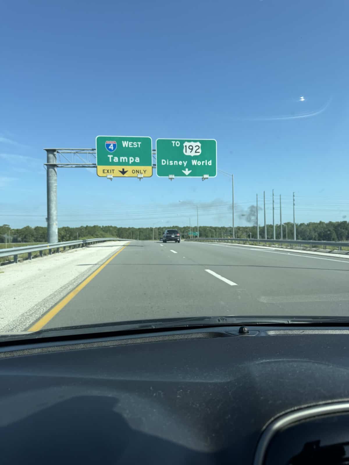 Smooth highway with prominent signs pointing to I-4 West for Tampa and 192 leading right to Disney World, stretching out under a bright blue sky—showcasing the peaceful start of what would become an eventful morning near the world-famous park.