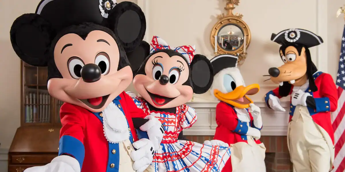 Mickey, Minnie, Donald, and Goofy in colonial outfits pose by a flag inside Disneyland as fireworks viewing areas are blocked.
