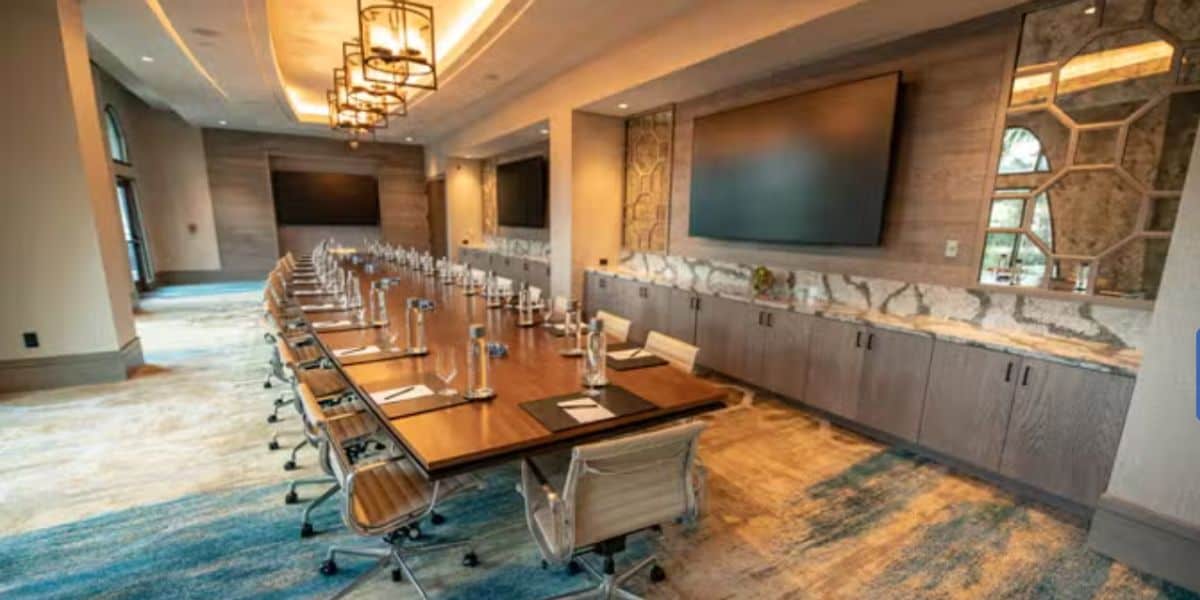 State-of-the-art meeting room featuring a long table surrounded by chairs, notepads ready for creative planning, and big screens displaying park updates—perfect for discussing upcoming attraction closures at Walt Disney World Resort or organizing guest support when schedules change.