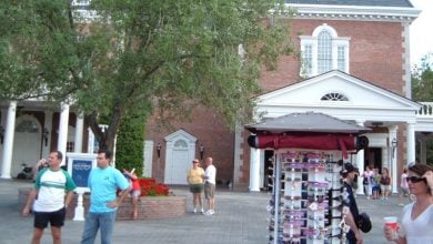 Guests gather by the sunglasses kiosk just outside the main entrance of the American Adventure Pavilion at EPCOT