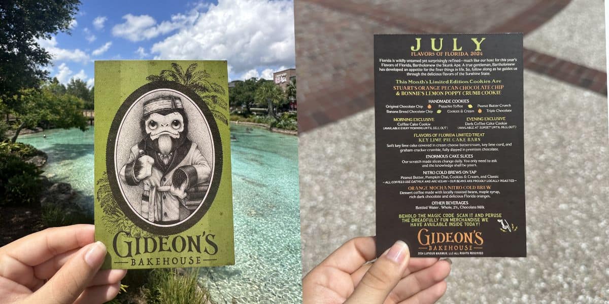 Guests at Disney Springs hold up Gideon's Bakehouse July menu cards outside, set against a backdrop of turquoise water and lush trees, showcasing the detailed designs that make Gideon's a must-visit dessert destination for theme park fans.