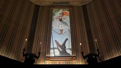 The iconic Haunted Mansion stretching portrait featuring the young woman with a parasol delicately perched above an alligator.
