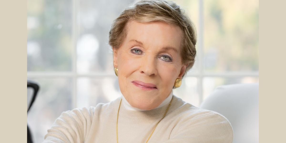 Joyful older woman with a chic short hairstyle and gold earrings enjoying the relaxing ambiance of a cozy lounge in a theme park resort, bathed in cheerful, soft lighting.