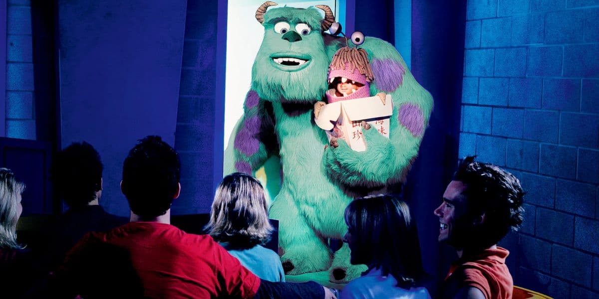 Sulley and Boo from Monsters, Inc. delight the audience under vibrant lights during a lively stage show at the park.