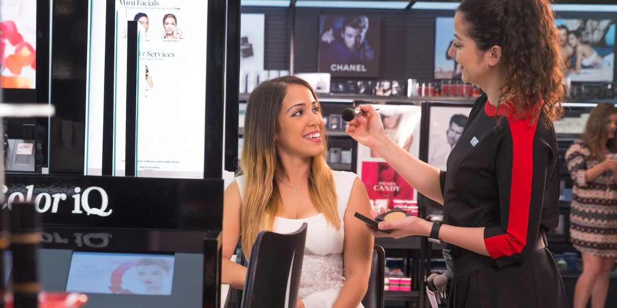 A talented makeup artist gives a magical makeover to a delighted guest in the vibrant beauty boutique at Universal Studios, surrounded by themed decor and shelves of colorful cosmetics.
