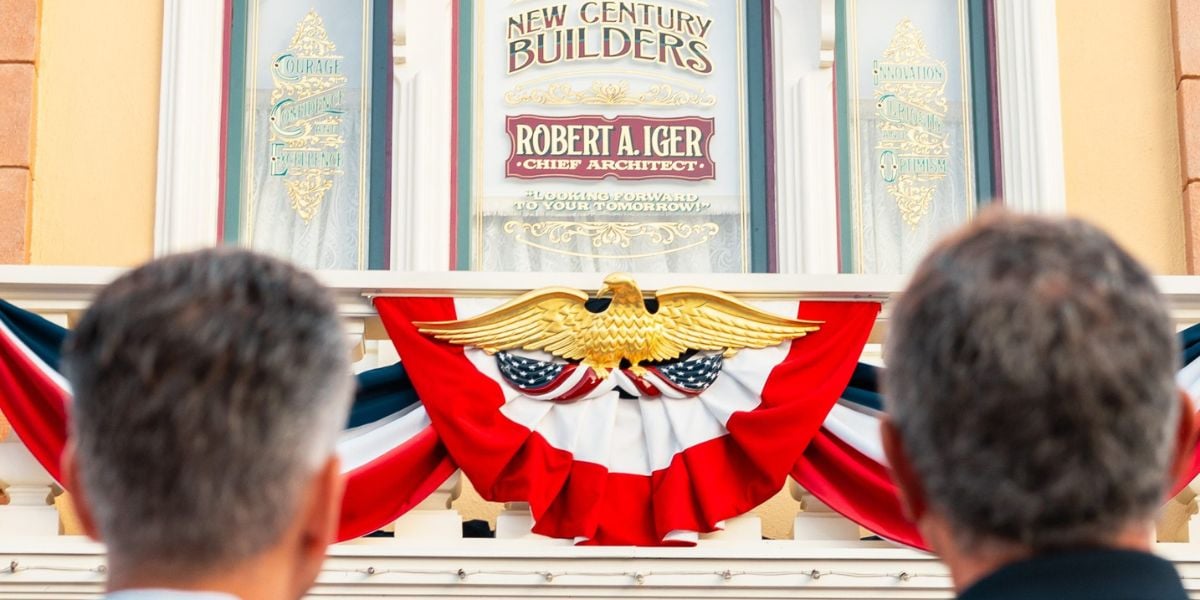 Guests admire a vibrant red, white, and blue installation featuring a majestic eagle and the “New Century Builders” sign, evoking a classic Americana theme park atmosphere.
