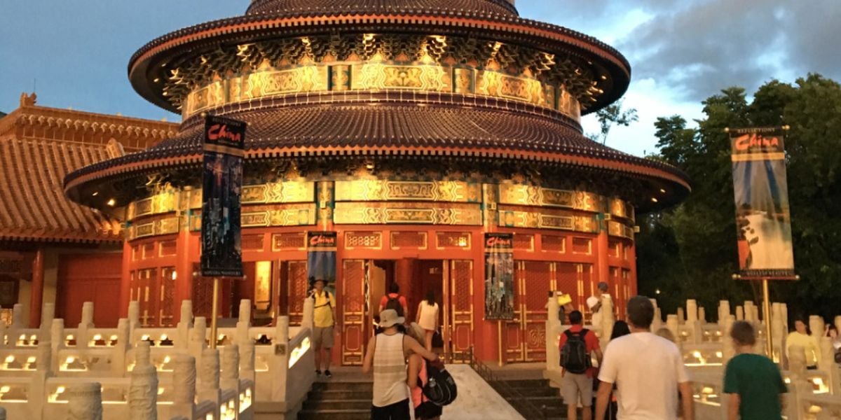 Guests stroll toward the China World Showcase Pavilion at EPCOT at dusk.