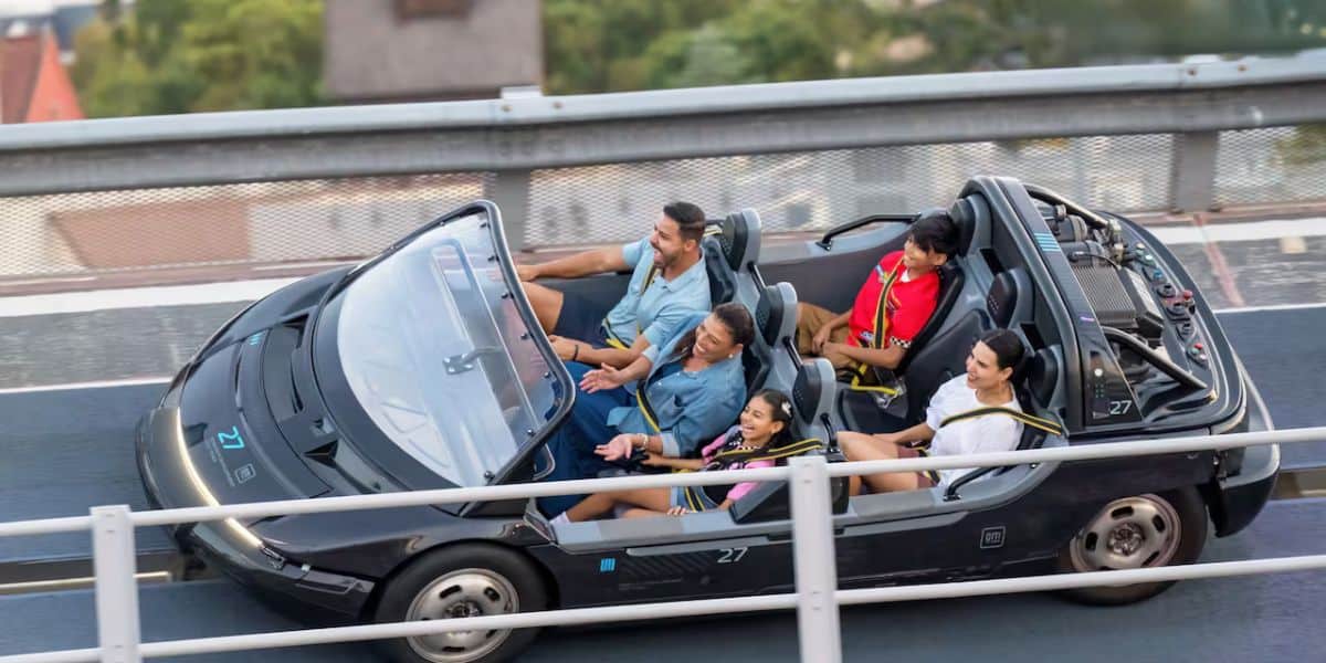Test Track at EPCOT is back in action, with four guests grinning as they race along the track in a sleek black convertible ride vehicle—completely caught up in the thrill after the attraction’s mysterious 24-hour downtime.