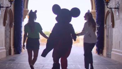 Disney World guests walk with Mickey Mouse in Magic Kingdom
