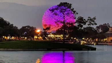 Spaceship Earth lit up behind the World Showcase Lagoon at EPCOT at dusk.