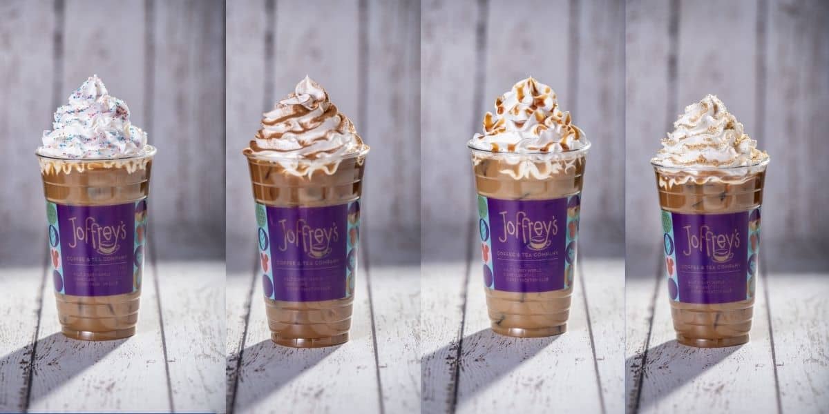 Four frosty Joffrey’s iced coffee drinks topped with whipped cream sit ready for guests on a white wooden table, perfect for an energizing pick-me-up during your Disney park adventure.