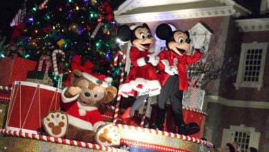 Mickey and Minnie Mouse, dressed in festive holiday attire, wave to guests at Magic Kingdom.