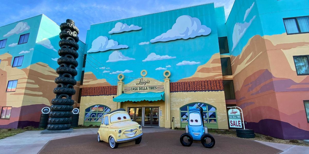 The entrance to Disney World’s Art of Animation Resort welcomes guests with eye-catching Cars movie murals, two life-sized car statues, and a towering stack of black tires on the left—an unforgettable landmark for fans arriving in 2027.