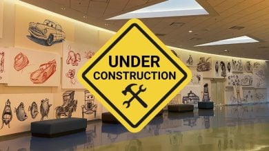 An oversized “Under Construction” sign stretches across a mural of Cars characters and beloved Disney favorites inside the Art of Animation Resort, signaling exciting updates coming to this fan-favorite Disney World hotel in 2027.