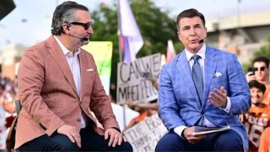 Sports commentators on a lively TV set chat in front of enthusiastic Texas fans waving signs, creating an atmosphere full of excitement like the energy found at a major theme park event.