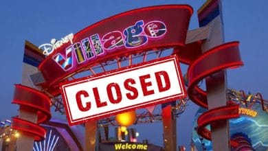 Disney Village aglow at night with a bold “CLOSED” sign stretched across its entrance, marking the upcoming closure of Disneyland Paris at the end of 2026 for fans and visitors.
