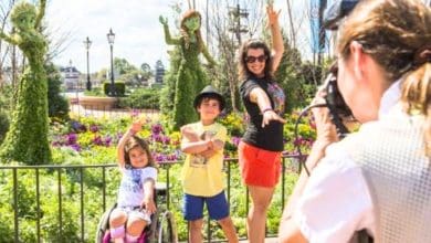a young guest in a wheelchair takes a picture with her family at EPCOT
