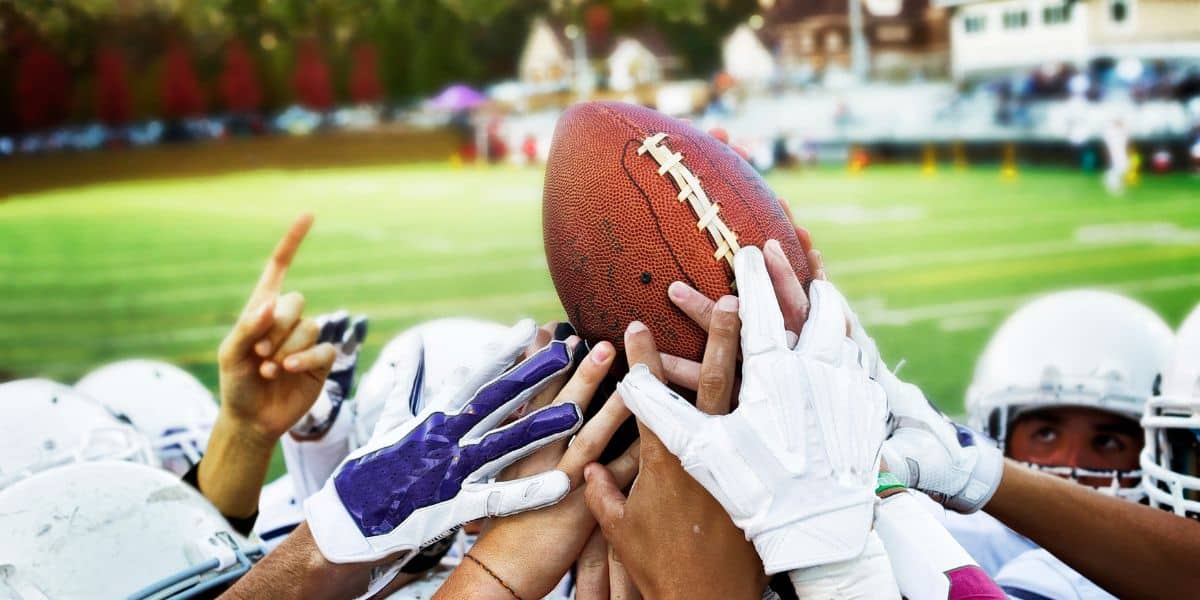 College football players reach for football