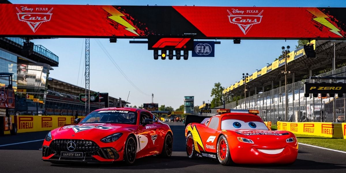 Lightning McQueen and a red Mercedes AMG await race fans on a Formula 1 track beneath the starting banner, ready for thrilling photo ops and excitement.