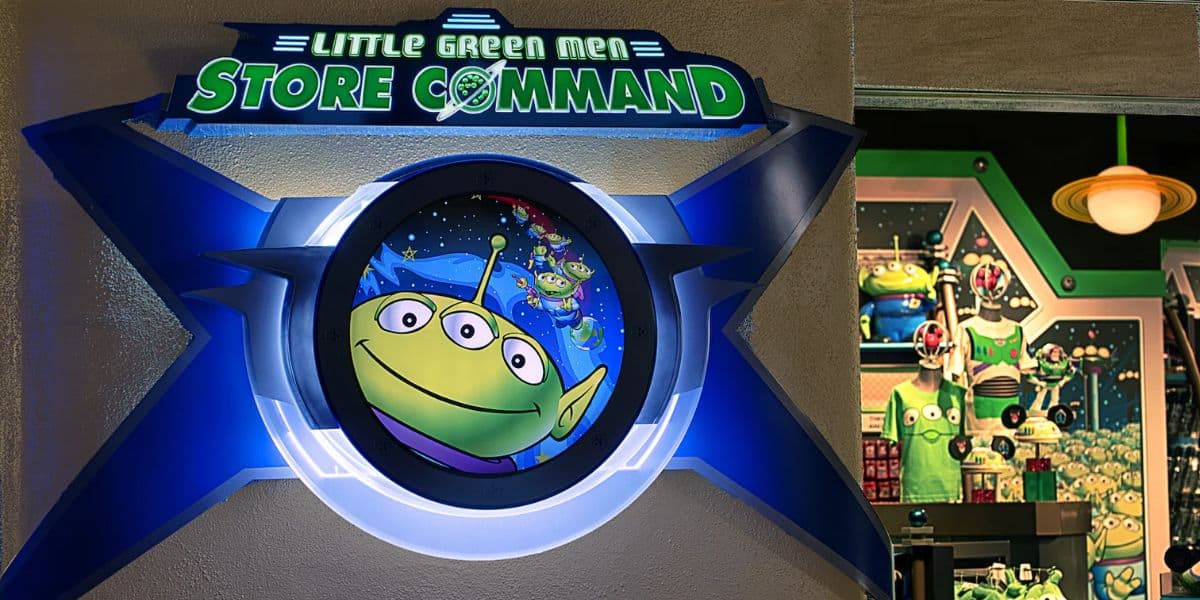 Little Green Men Store Command entrance sign featuring a whimsical alien graphic, located next to an out-of-this-world shop filled with Toy Story-themed alien merchandise in Tomorrowland at Disneyland.