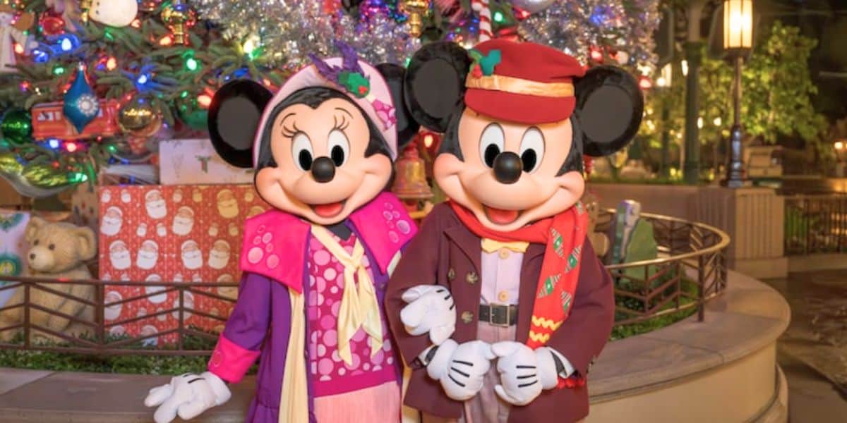Minnie and Mickey Mouse, dressed in their festive winter best, pose together in front of a sparkling Disneyland Christmas tree, excitedly showing off the season’s must-have holiday popcorn bucket that’s quickly gained viral status among park guests.