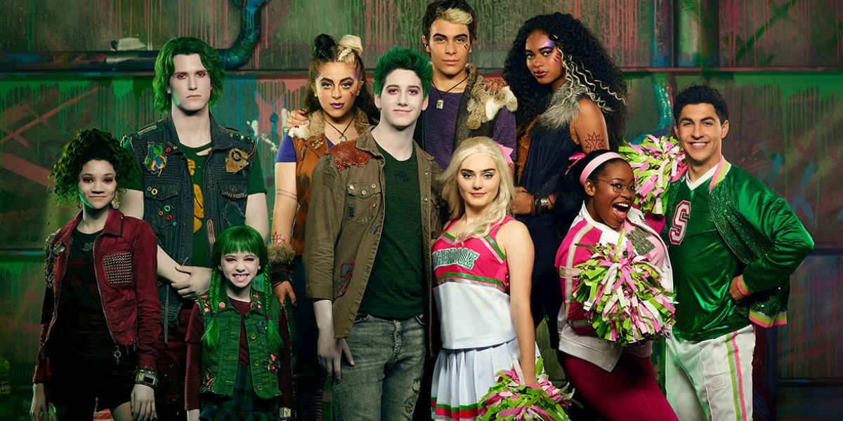 Fans decked out in vibrant, Disney Channel-inspired costumes gather for a group photo; some sport green wigs and face paint, while others wave pom-poms, channeling the high-energy spirit seen in Carla Jeffery’s standout performances.