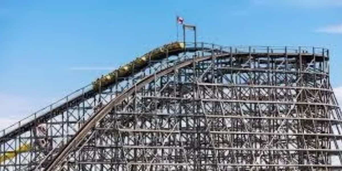 A roller coaster train cresting the lift hill on a wooden coaster at Six Flags.