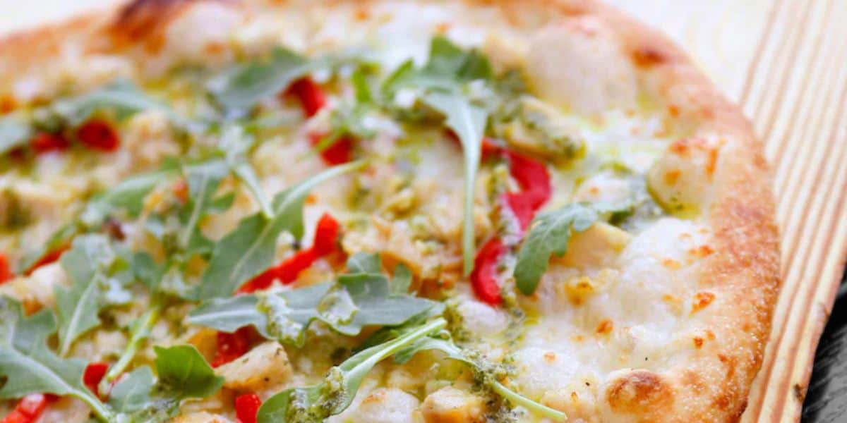 A Blaze Pizza topped with pesto, chicken, red peppers, and fresh arugula, served as a quick-service meal at the theme park.