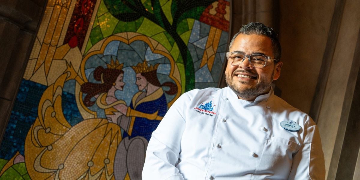 A Chef de Cuisine in front of the Cinderella mosaic at Be Our Guest Restaurant in Magic Kingdom.