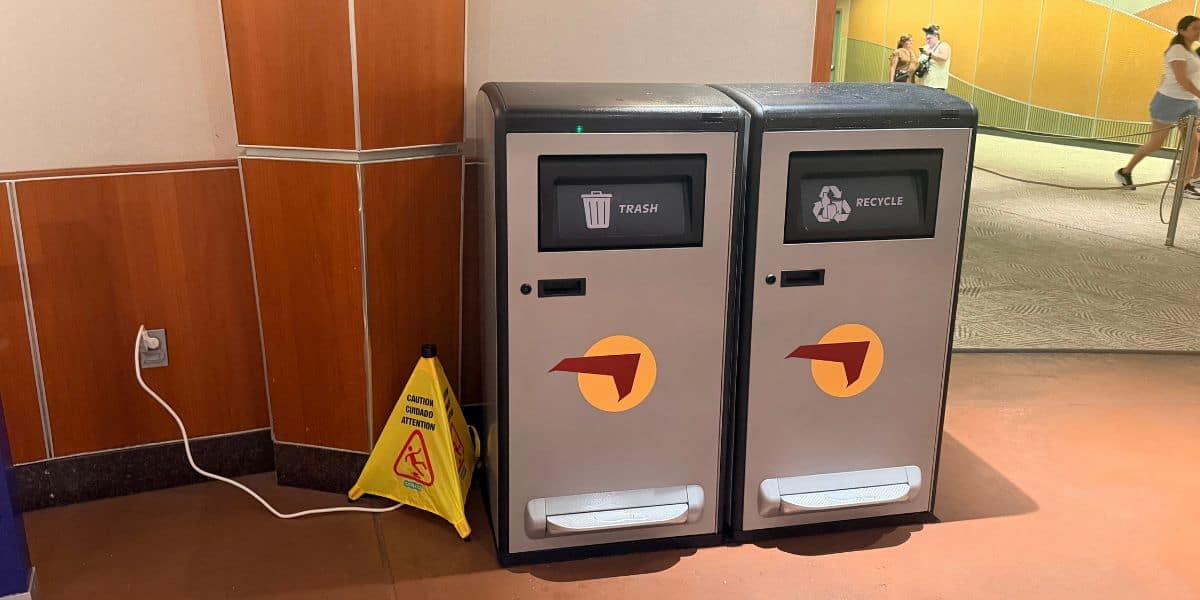 Trash and recycling bins by a First Solar wet floor sign at Disney World.