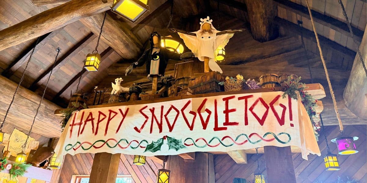 Toothless and Light Fury figures above a Happy Snoggletog banner at the How to Train Your Dragon land in DreamWorks Land.