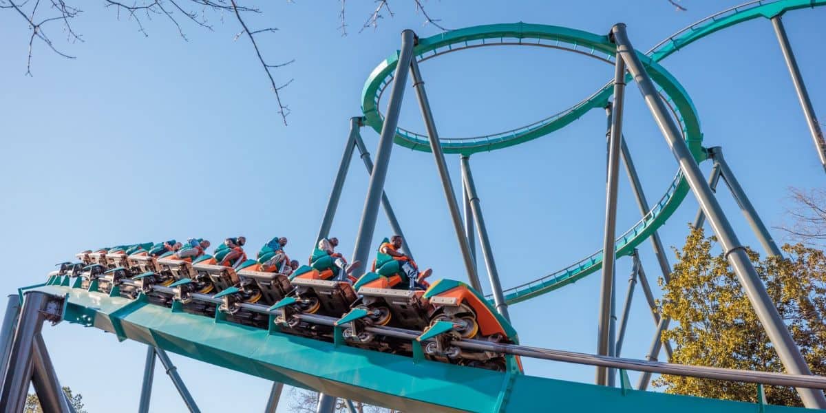 Thrill-seekers on a teal roller coaster looping through the inversion.