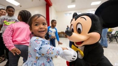A young girl shaking hands with Mickey Mouse during a Disney visit to North Carolina.