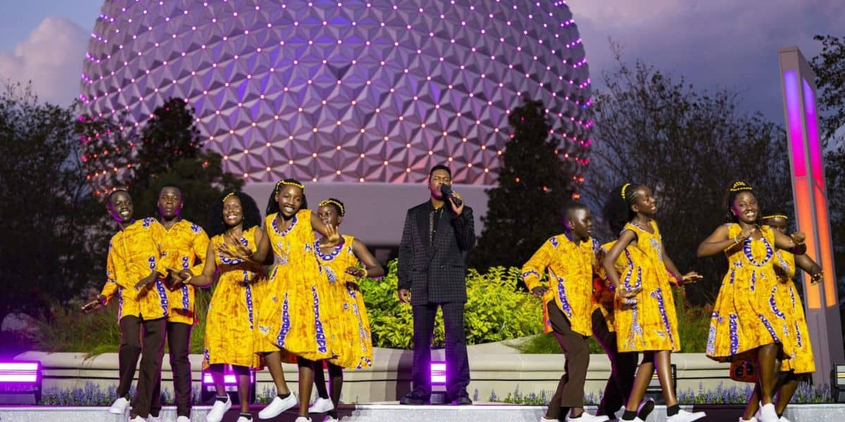 Performers and a singer on stage in front of Spaceship Earth during the Disney Holiday Special at EPCOT.